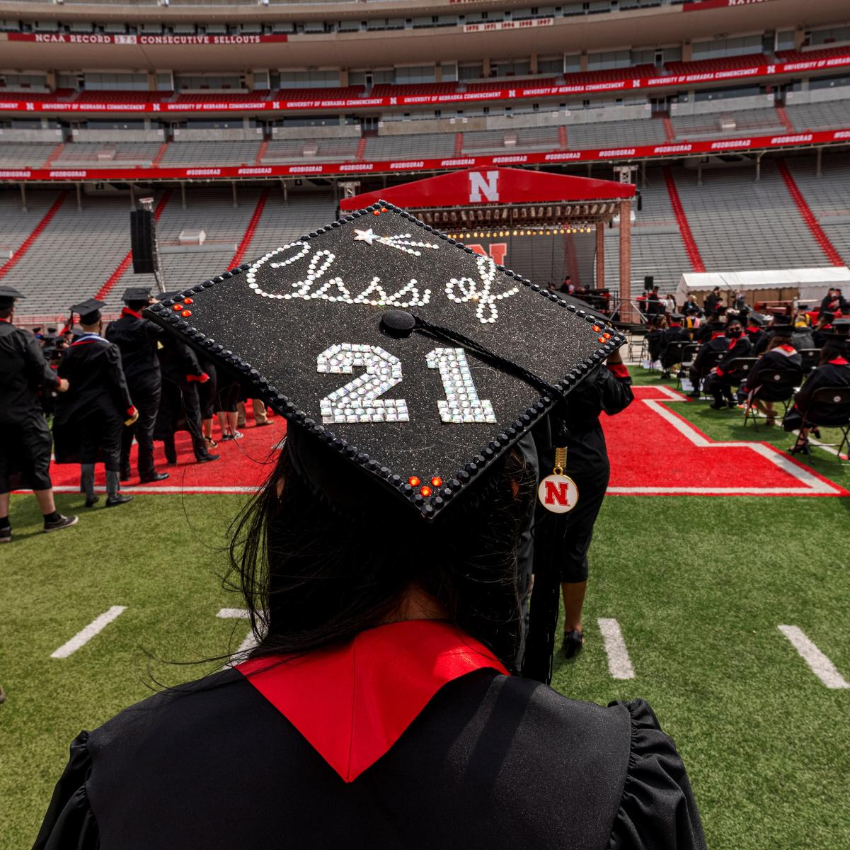 A UNL graduate shows her mortar board standing on Memorial Stadium field for spring commencement