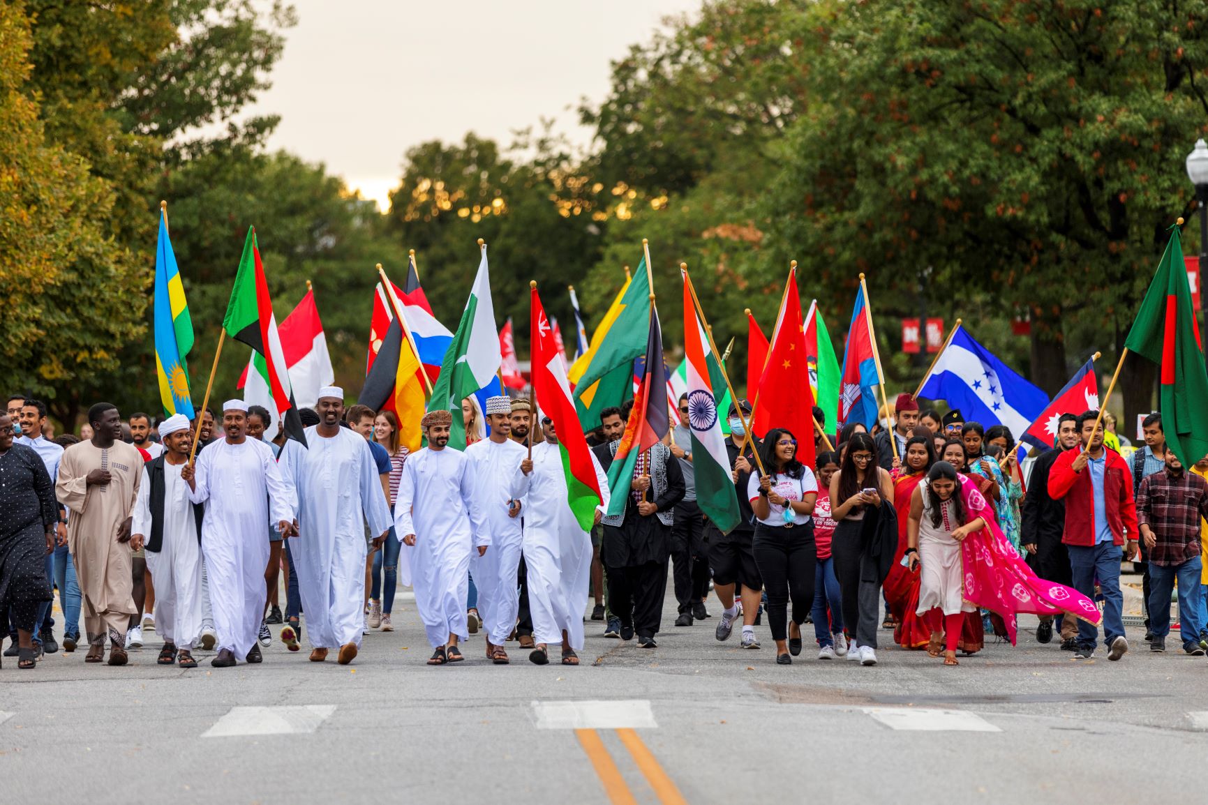 Several international students in national attire carry their national flags during the Homecoming 2021 parade