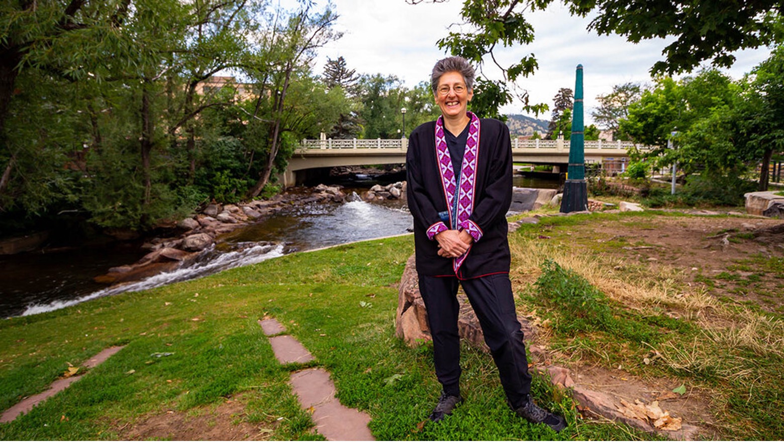 Sarah Michaels, professor of political science at Nebraska and a faculty fellow with the University of Nebraska Public Policy Center, smiles and stands outside by a creek.
