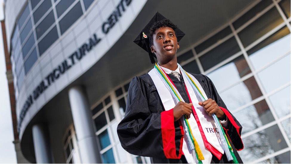 Khalid Yusuf, who served as a Diversity Ambassador, stands in his graduation regalia near the Gaughan Multicultural Center.